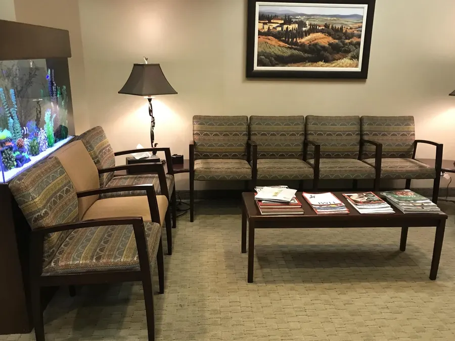 The waiting room, with an aquarium, a coffee table and landscape paintings.